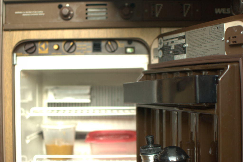 An open RV absorption refrigerator showing the interior shelves and control panel