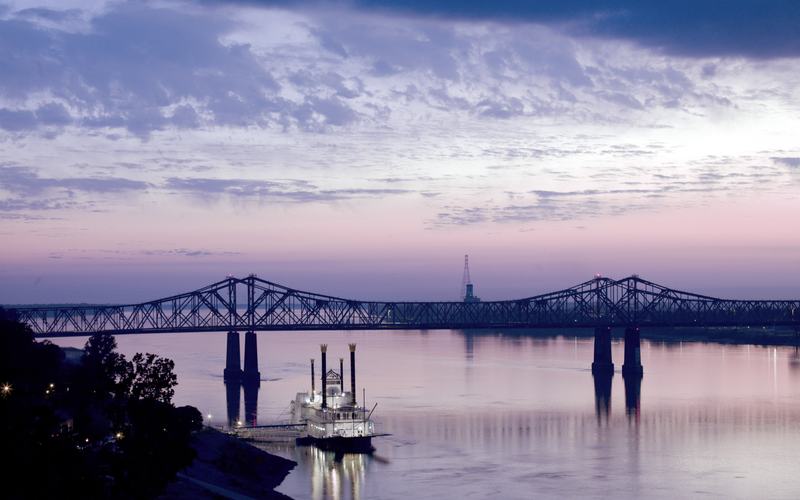 The Mississippi River at Natchez with a paddlewheeler and the bridge at dusk, Mississippi